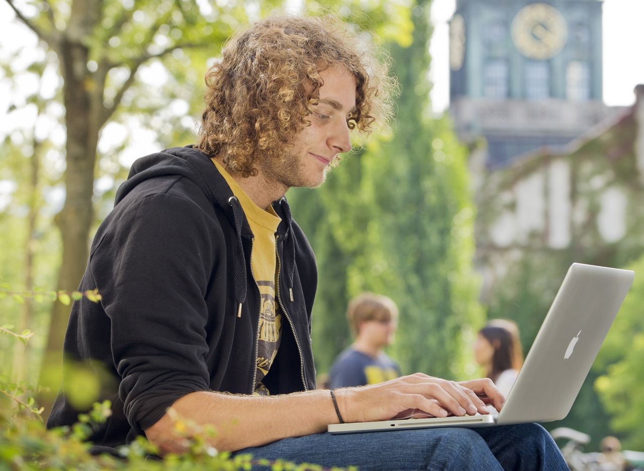 Student mit Laptop auf dem Campus